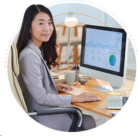 An outsourced financial analysts working on a computer at a desk with graphs and charts on the screen